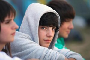 a hooded teen boy considers entering an anger management program