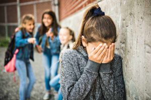 three teenagers making fun of a fourth as she cries on the playground and wishes she knew 10 ways to stop bullying