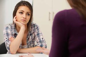 serious teenage girl listening as a therapist explains how a bipolar disorder treatment program can help