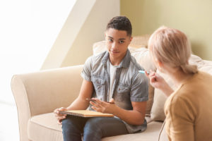 teenage boy learning about outpatient mental health treatment for teens from a therapist