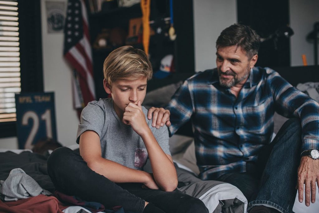 father consoling his young son and demonstrating the 5 activities for teaching grief and coping skills to teens.