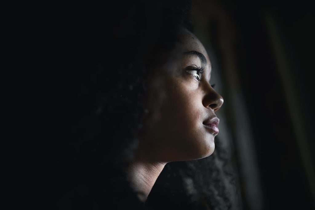 shadowed profile of a depressed young woman displaying one of the 5 sings of emotional trauma in a teen