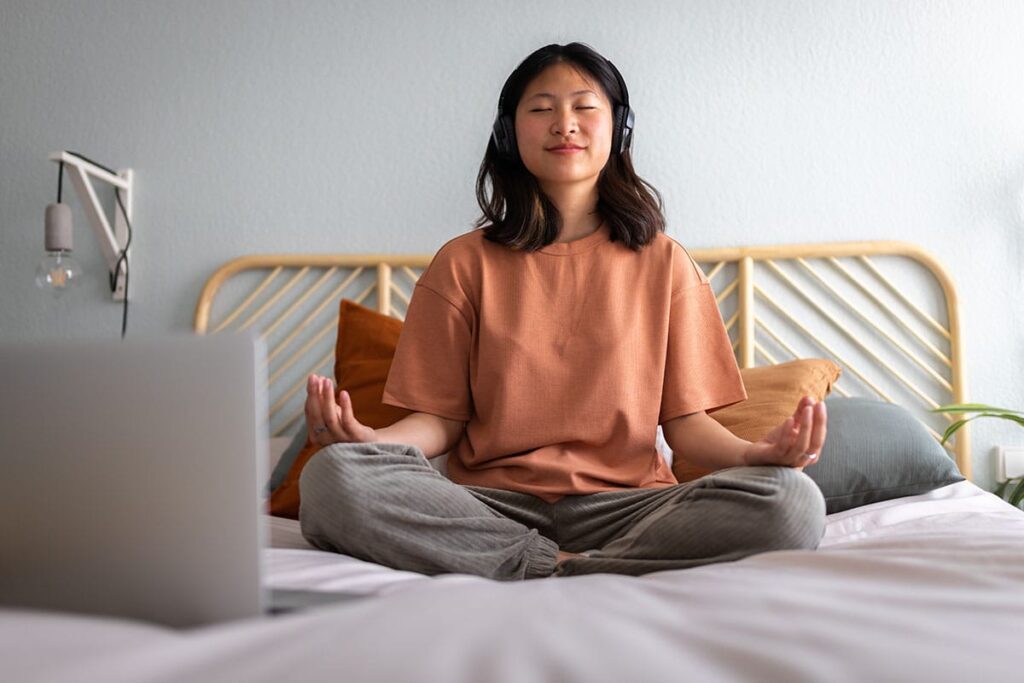 female teenager sitting on bed and mediating as one of 5 ways to cope with anxiety as a teen