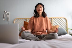 female teenager sitting on bed and mediating as one of 5 ways to cope with anxiety as a teen