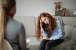 teenage girl sitting on couch in office setting looking frustrated as therapist explains what to expect in adolescent IOP