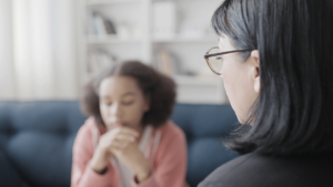 female behavioral health therapist helping despondent adolescent girl by employing one of 5 crisis intervention strategies for adolescents.