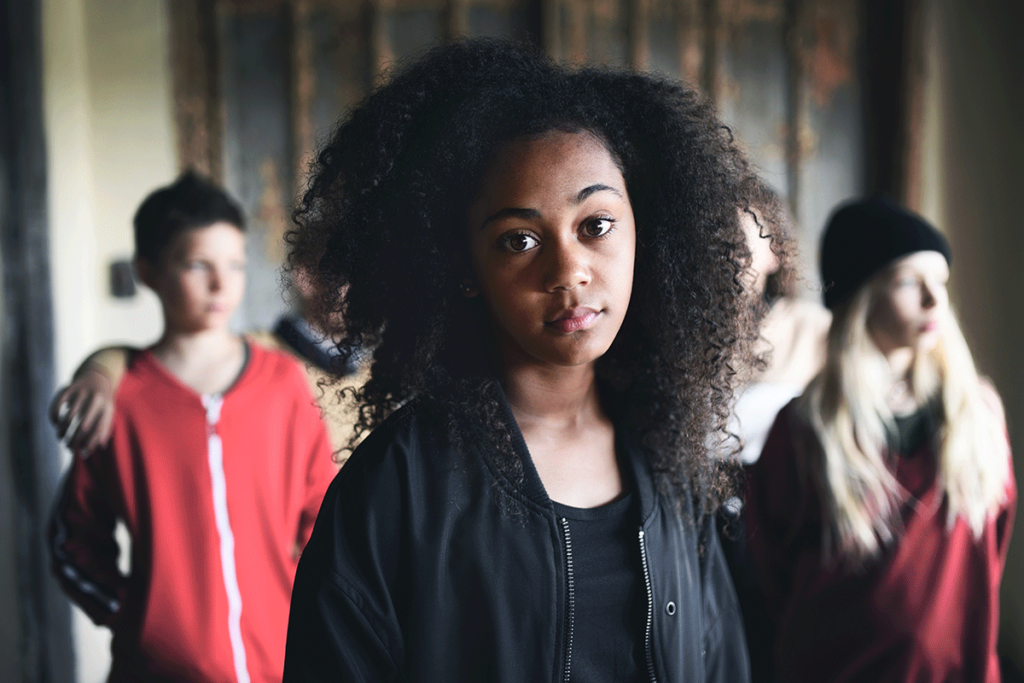 teenage girl staring at camera and surrounded with her peers in the background in need of the 6 stages of teenage crisis intervention