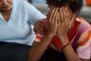 a teen breaks down and is comforted by a parent in the aftermath of an extreme mood swing