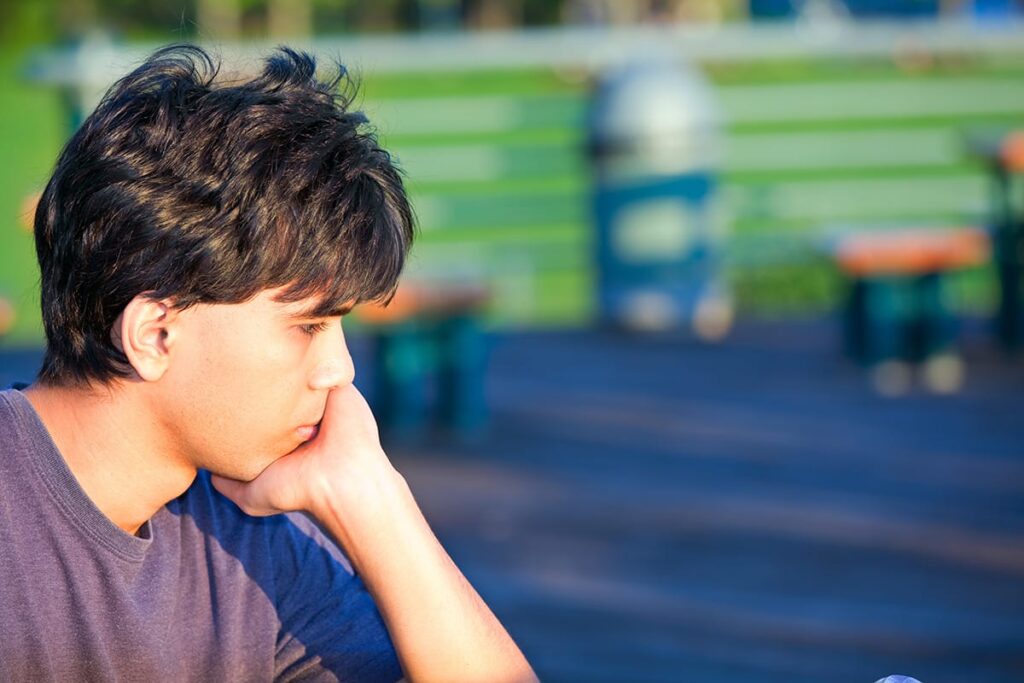 teenage boy seated alone on bleachers and taking a moment as one of 3 tips on coping with anger