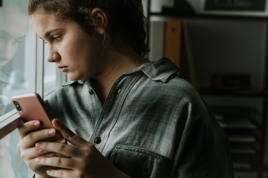 serious young woman is finding anxiety treatment in Nampa, ID, on her phone.