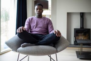 teenage boy seated in lotus position in chair learning how meditation helps your mental health